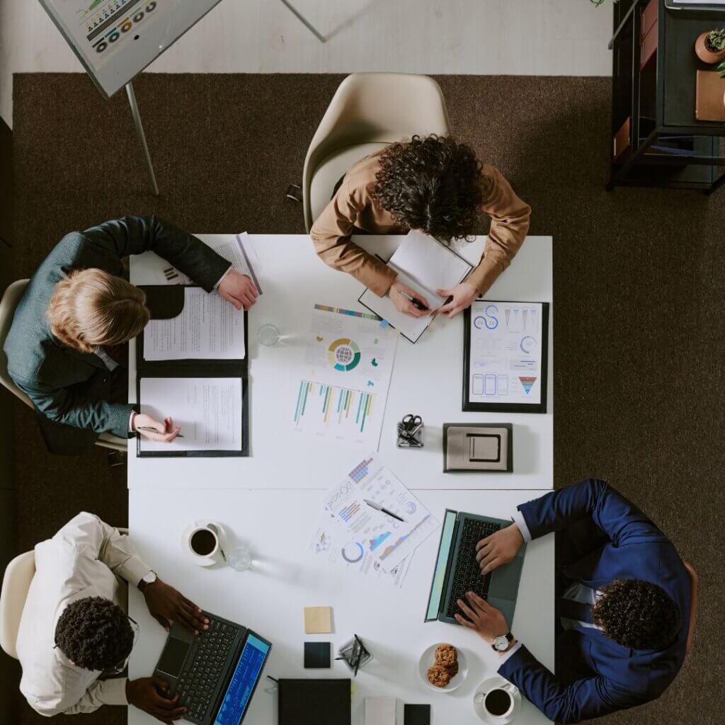 Overhead view of a team reviewing marketing data, charts, and laptops during a strategy meeting.