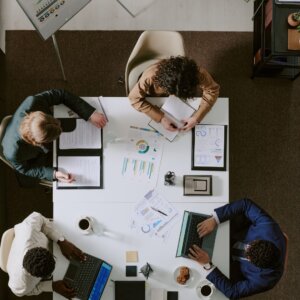 Overhead view of a team reviewing marketing data, charts, and laptops during a strategy meeting.